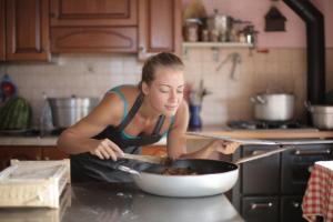 Mujer cocinando y oliendo la comida en la cocina de casa